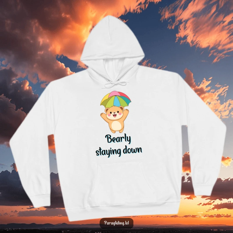 Funny hoodie with a joyful, round bear cub paragliding under a colorful canopy, designed for comfort and expressing a love for adventure.