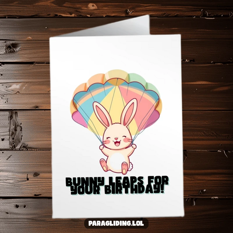 Free Printable Birthday Card: A cheerful bunny dangles with delight from a colorful parachute, enjoying the ride.