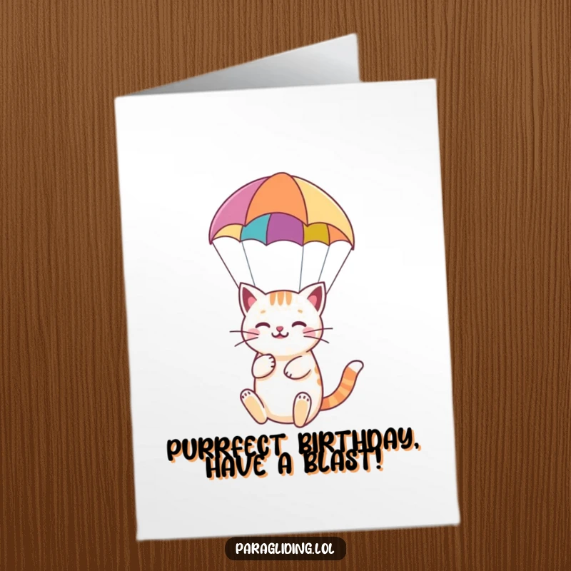 Funny Free Printable Birthday Card: A blissful cat floating peacefully beneath a colorful paraglider, celebrating a birthday in style.