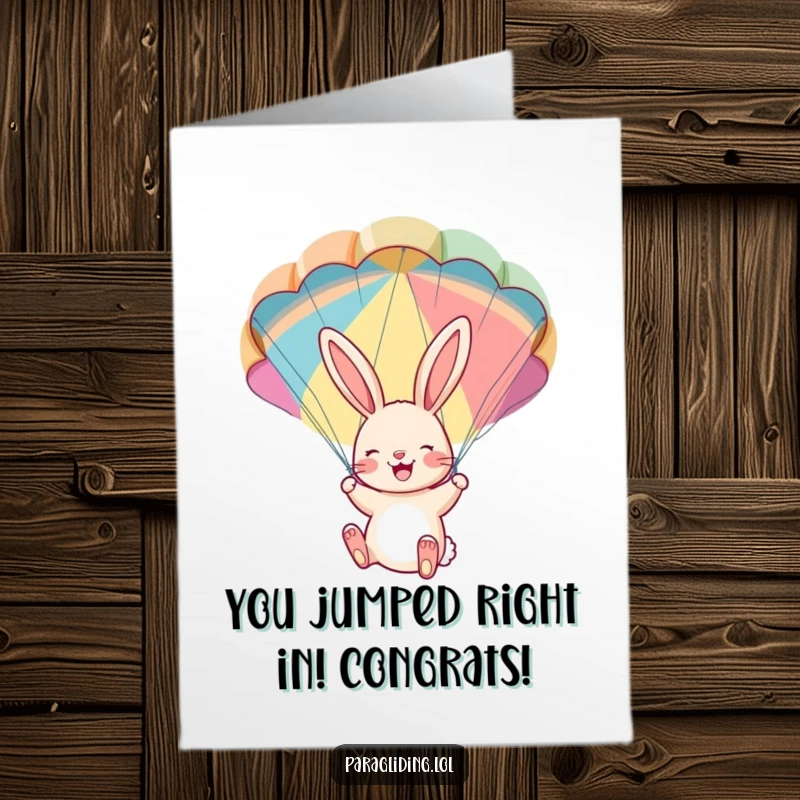 Free Printable Congrats Card: A cheerful bunny hangs from a colorful parachute, looking delighted after a successful journey.