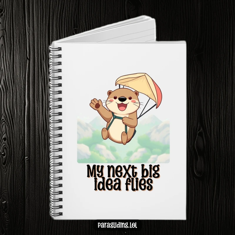 Funny notebook with a happy otter waving from a paraglider high above, ideal for jotting down ideas and adventures.